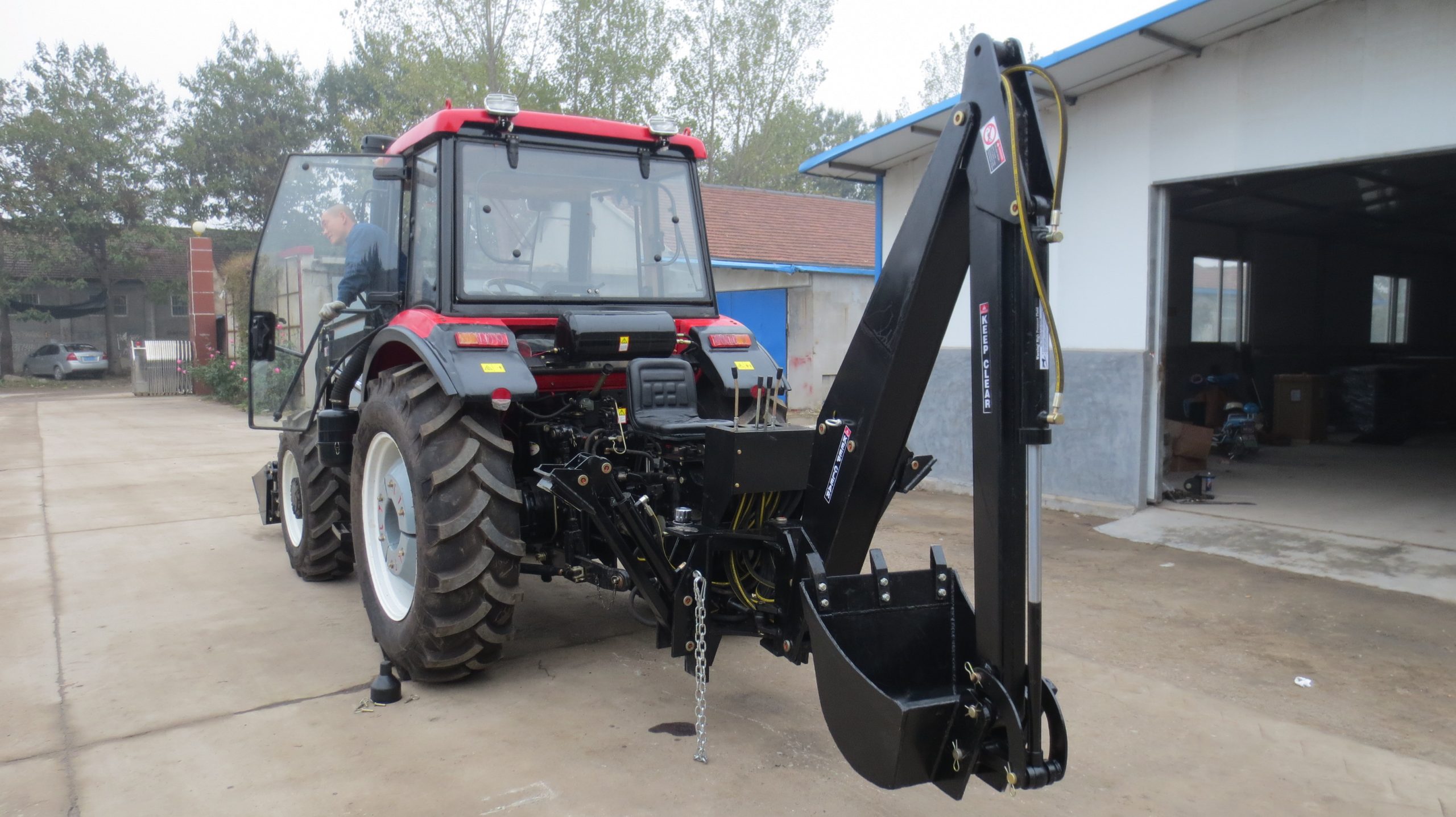 Red tractor with backhoe at rural workshop