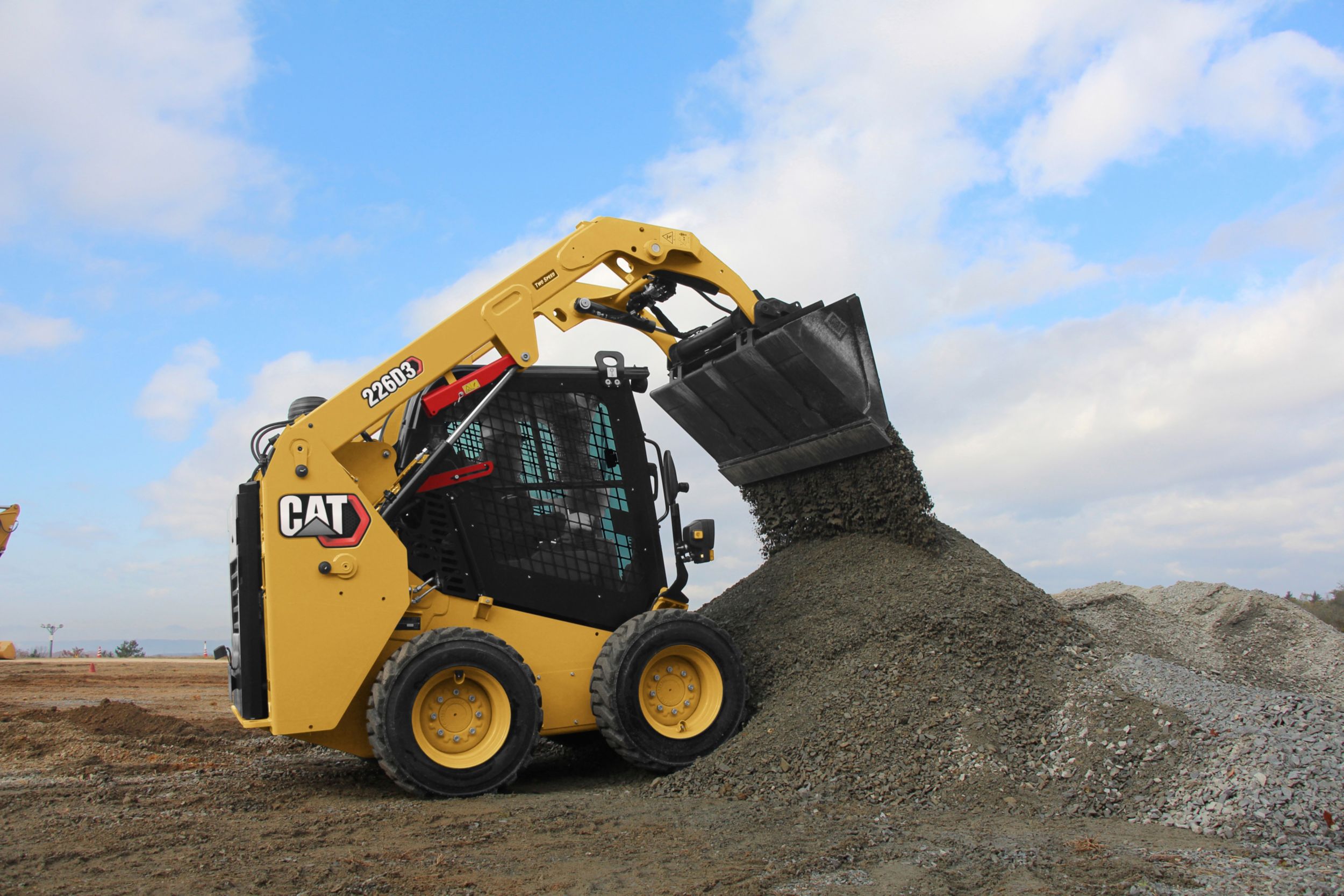 Yellow CAT skid steer loader moving gravel