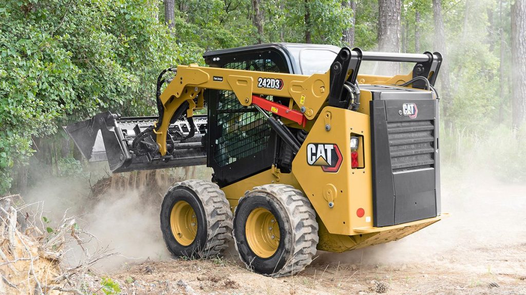 CAT skid steer loader operating in wooded area