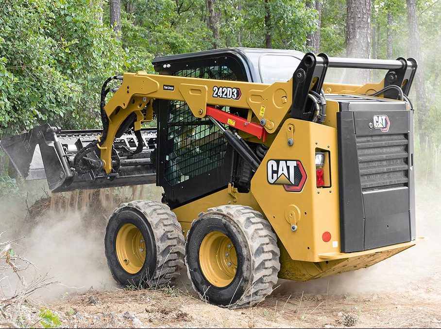 CAT skid steer loader operating in wooded area