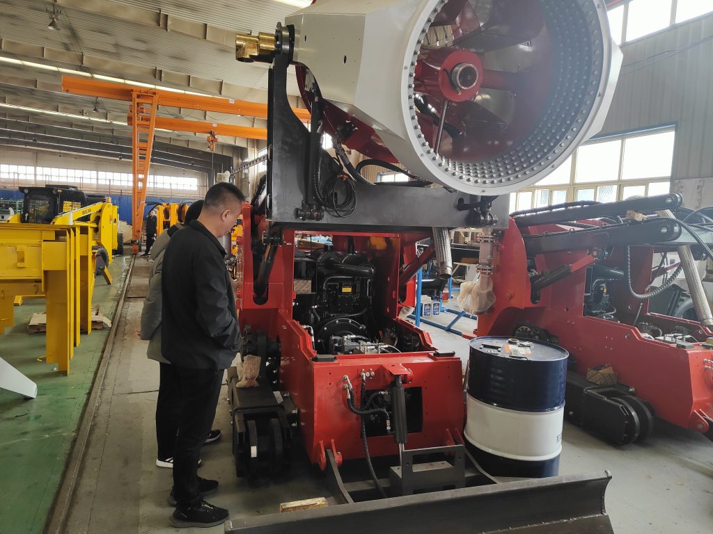 Technician inspecting large red agricultural machinery in factory