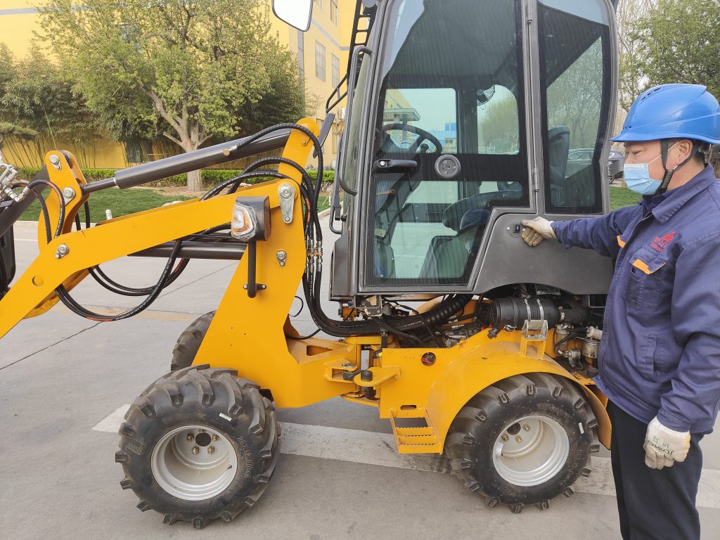 Worker inspecting yellow backhoe loader outdoors