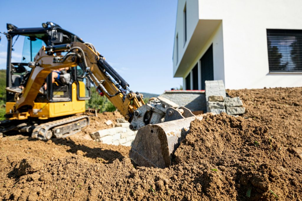 Mini excavator digging preparing ground under home garden