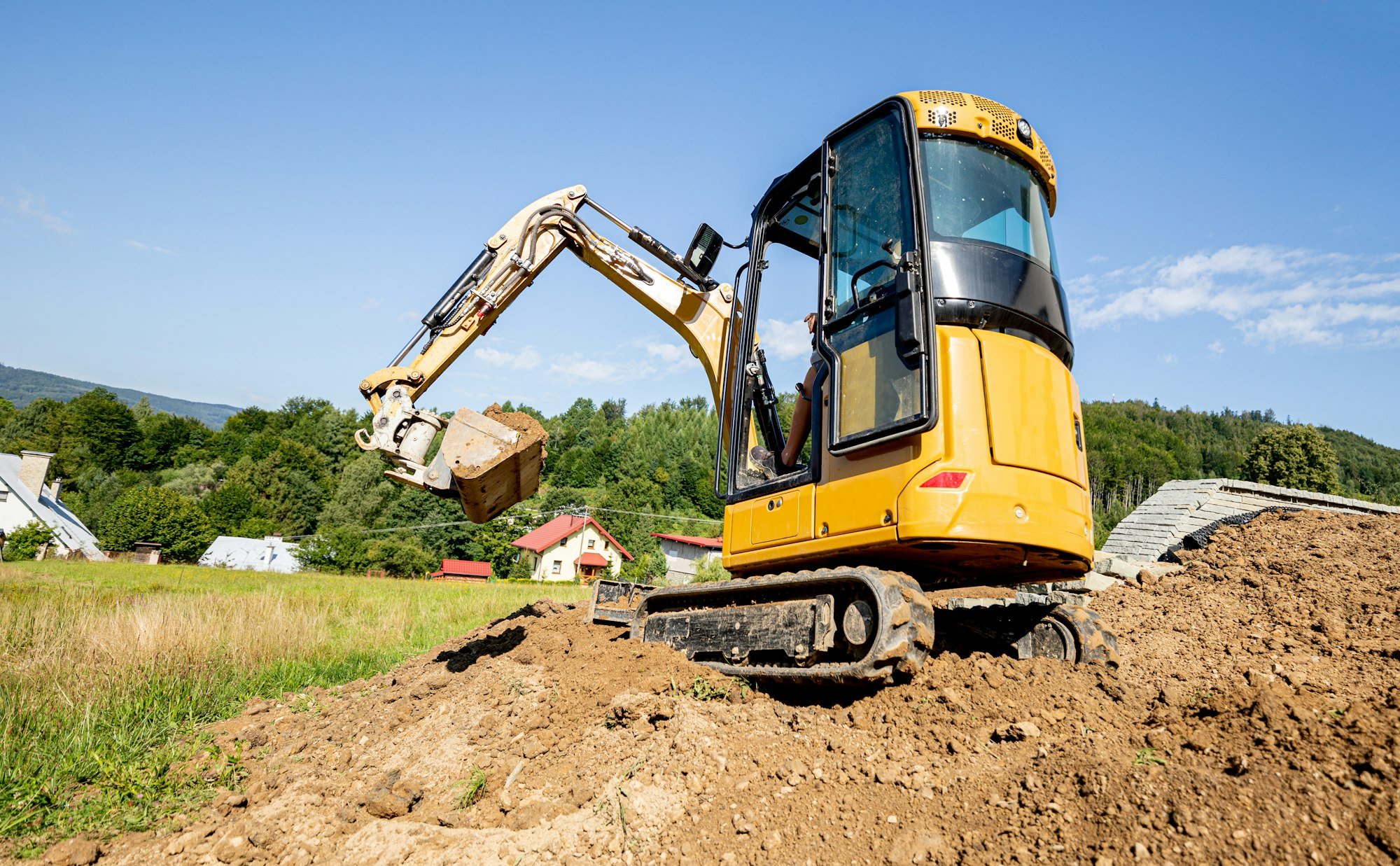 Mini excavator digging preparing ground under home garden